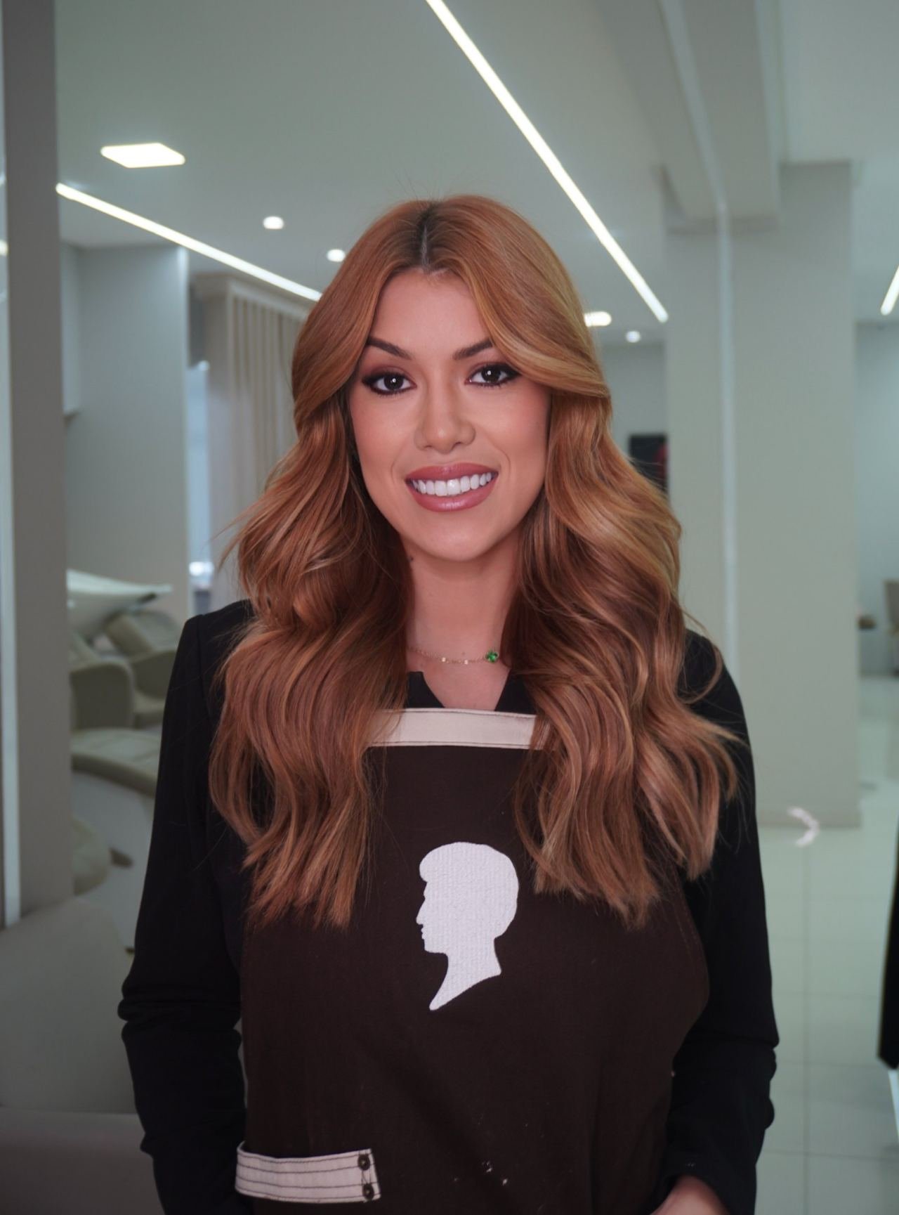 Thalia Ferraz, cabeleireira, sorrindo no salão